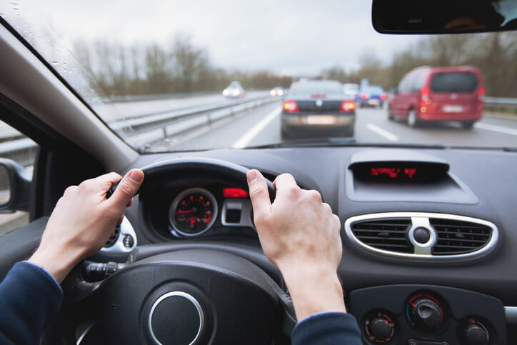 Vista desde el asiento del conductor sujetando el volante con tráfico adelante en la autopista